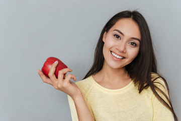 Cheerful charming young woman holding red apple