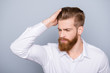 Portrait of confident man with red beard touching his hair