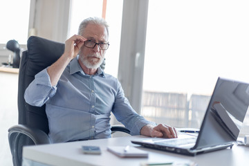 Portrait of businessman sitting in office, hard light