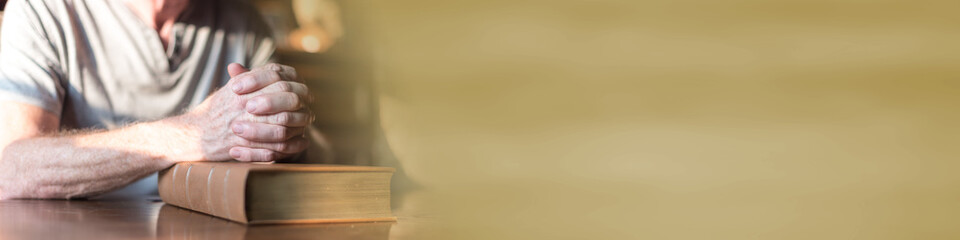 Man praying with his hands over a bible