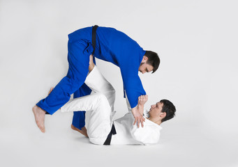 Young sporty men practicing martial arts on light background