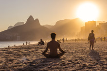 Man On Yoga Pose During A Sunset On Ipanema Beach With Morro Dois Irmãos On The Background, Rio De Janeiro, Brazil