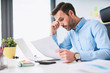 © baranq - Unhappy businessman doing paperwork at office