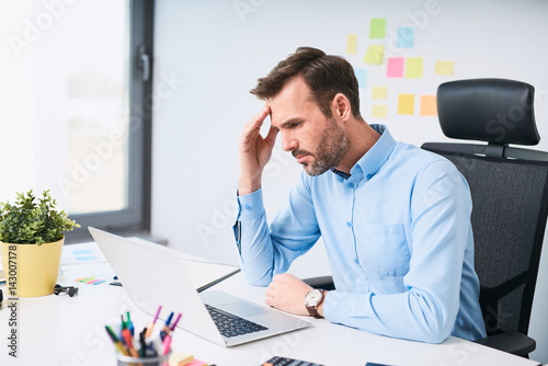 Fotografía Worried businessman working on laptop at office