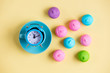 photo of tasty colorful marshmallows and alarm clock on plate on the wonderful yellow background