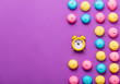 photo of tasty colorful marshmallows and alarm clock on the wonderful purple background