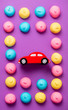 photo of tasty colorful marshmallows and car shaped toy on the wonderful purple background