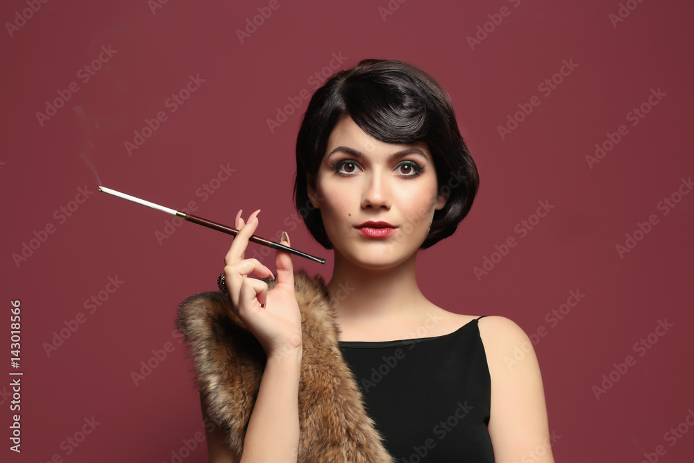 lady with cigarette holder Young woman smoking with cigarette holder on color background Stock Photo