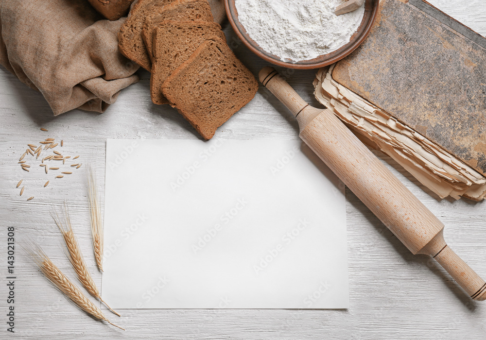 Sheet of paper with space for text and bread on wooden background