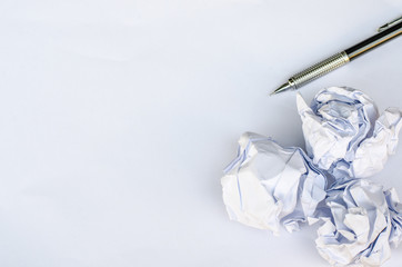 Writing concept - crumpled up paper wads with a sheet of white paper and pencil.