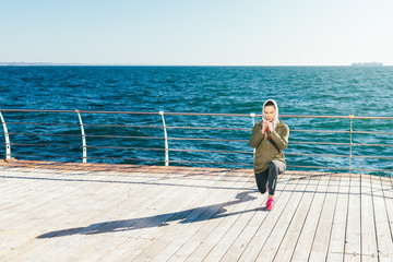 Wall Mural - Spring morning on the beach young woman doing sports exercises against the sea