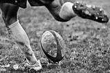Legs of rugby player kicking ball