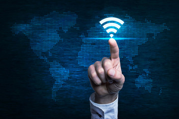 Canvas Print - hand pointing to wi-fi button over digital world map.