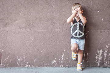 Sad boy over textured wall background with space for text