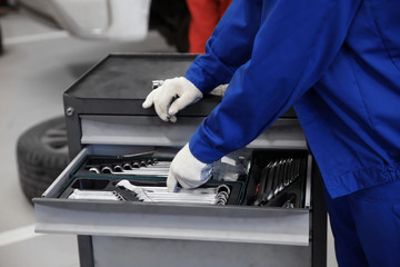 Mechanic in uniform near tools box, closeup