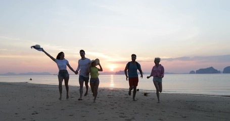 Wall Mural - young people group on beach at sunset, friends walking seaside, tourists sea vacation slow motion 60