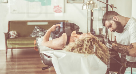 Wall Mural - Professional bearded tartist making tattoo in his own ink studio on young blond woman