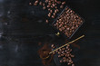Roasted coffee beans and grind coffee in wood box with spoon over black wooden burnt background. Top view with space.