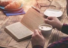 Man Eating French Breakfast And Reading Book