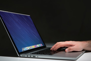 Hand typing on a keyboard of laptop with operating system screen on background