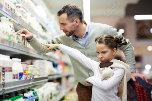 Valokuva Capricious daughter asking her father to buy her tasty yoghurt in supermarket