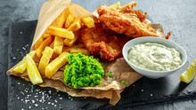 British Traditional Fish And Chips With Mashed Peas, Tartar Sauce On Crumpled Paper.