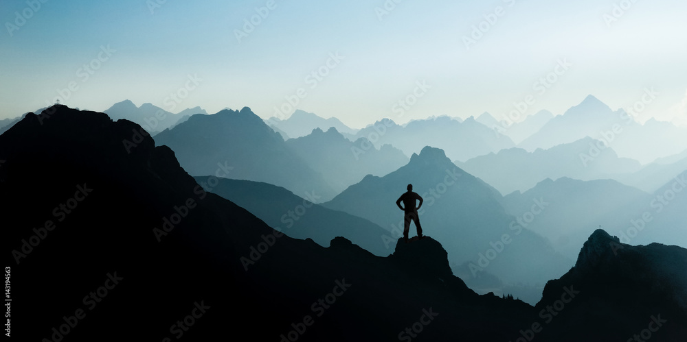 Spectacular mountain ranges silhouettes. Man reaching summit enjoying freedom. - obrazy, fototapety, plakaty 