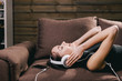 © luckyphoto - girl with headset lying on sofa and listen music