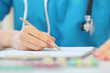 A female doctor sits at a table and makes a writing pen, photo with depth of field