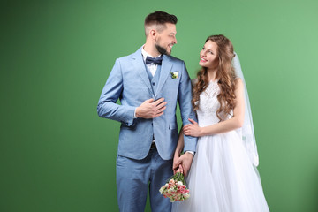 Wall Mural - Happy wedding couple posing on color background