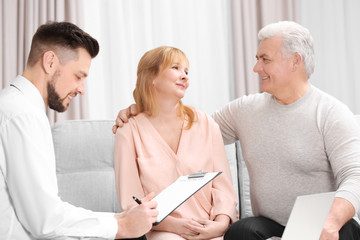 Sticker - Middle aged couple signing contract sitting on couch at home