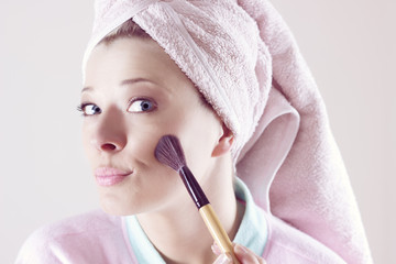 Beauty and make-up concept - Happy young beautiful woman applying makeup on face by brush