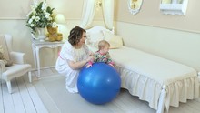 Mom Rolls A Little Daughter On A Big Blue Ball