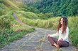 Yoga at Campuhan Ridge Walk, Bali Island. Young woman in lotus pose sitting on path. Concept of calm and meditation.