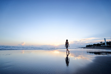 Sky and sea. Beautiful sunset. Silhouette of young woman walking on ocean beach.