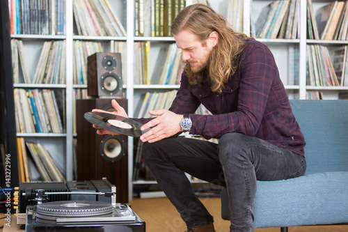 Poster long haired man putting a vinyl on the turntable