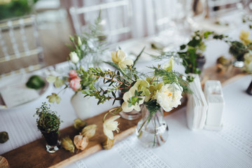 Wall Mural - On a serving buffet table there are compositions of flowers and plants in glass and ceramic vases on wooden stands