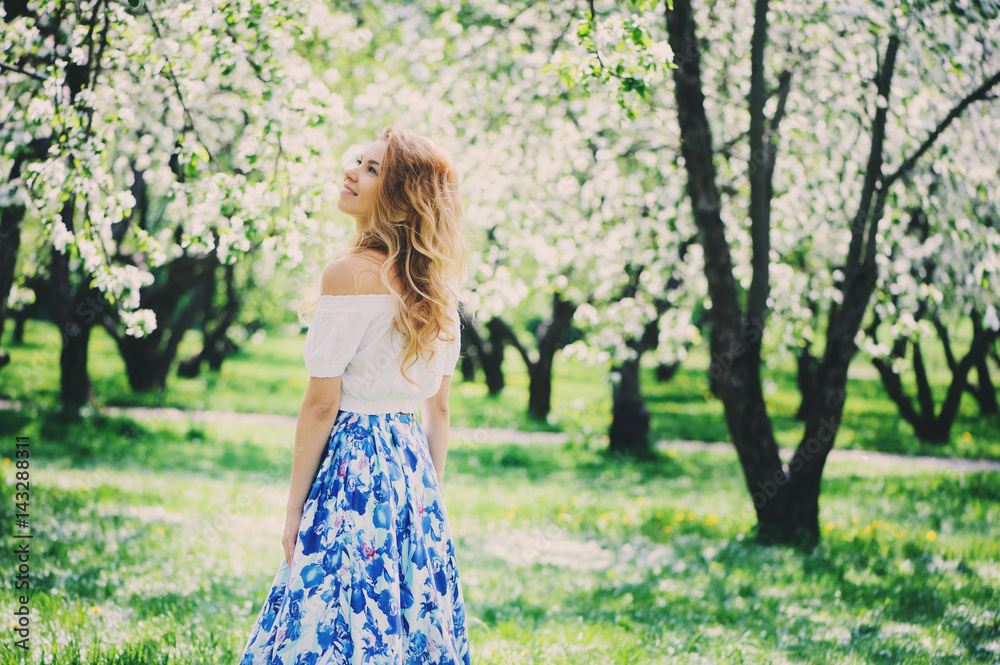 beautiful young woman in floral maxi skirt walking in spring