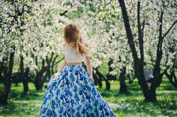 beautiful young woman in floral maxi skirt walking in spring