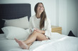 © Westend61 - Happy young woman sitting on bed with cup of coffee
