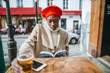Young woman in Paris drinking beer in cafe and reading a book