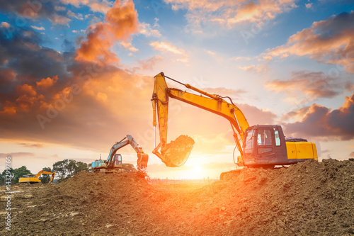 Fotografía excavator in construction site on sunset sky background