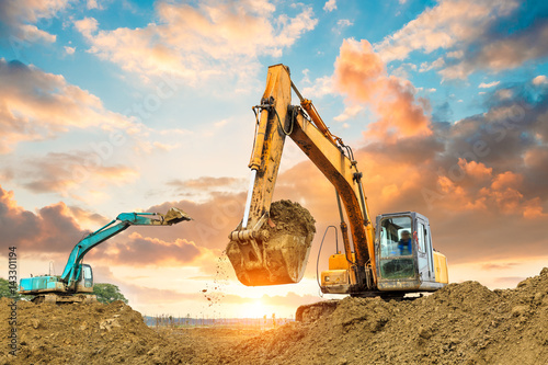 Fotomural excavator in construction site on sunset sky background