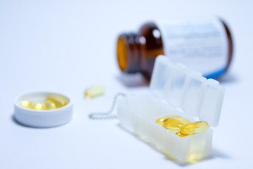 Yellow fish oil pellets are in the box and in a white cap bottle on the back side on white background.