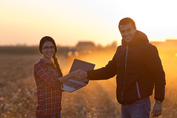 Wall Mural - Farmers shaking hnds at sunset