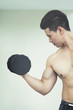 © eggeeggjiew - Asian Muscular man lifting dumbbells in gym. copy space.