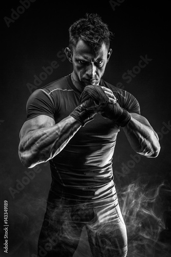 Studio portrait muscular man in smoke on black background Fototapete
