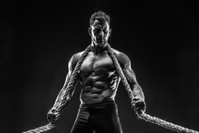 One Handsome Sexual Strong Young Man With Muscular Body Holding Rope With Hands Hanging On Neck And Shoulders Standing Posing In Studio On Black Background