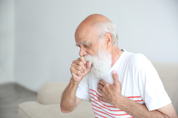 Wall Mural - Coughing senior man sitting on sofa