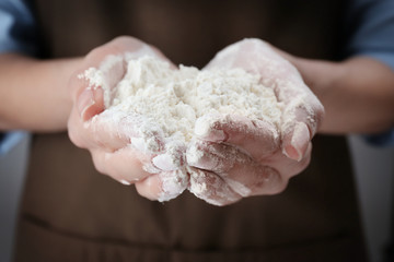 Poster - Woman holding heap of flour in hands, closeup